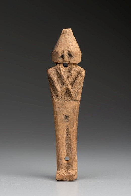Wooden ancient statuette depicting a human with their arms crossed on their chest